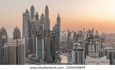 View of various skyscrapers in tallest recidential block in Dubai Marina aerial night to day transition with artificial canal. Many towers and yachts before sunrise