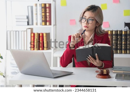 A knowledgeable and confident female lawyer working in an office with law books sitting at the table. Learn, and study, legal services, advice, justice, and real estate concepts.