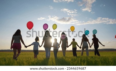 big family silhouette with balloons in park. large community family holding hands walking in nature silhouette in the park with balloons. happy family kid dream lifestyle concept