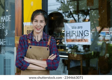 Close-up shot of a beautiful Asian coffee shop owner. small family job and the employment sign was affixed to the glass door. coffee shop woman standing in front of the shop with arms crossed