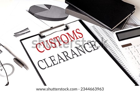 CUSTOMS CLEARANCE text on a paper clipboard with chart and notebook on withe background