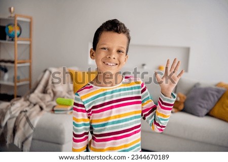 Portrait photo of cheerful friendly small guy waving hand friendly picture spend time playroom entertainment isolated indoors background Royalty-Free Stock Photo #2344670189
