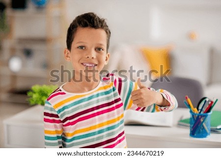 Portrait photo of cheerful positive schoolboy thumb up like gesture recommend spend his free time playroom isolated on flat background