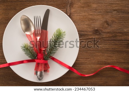 White empty plate with fork, spoon and knife tied with a ribbon on a table  