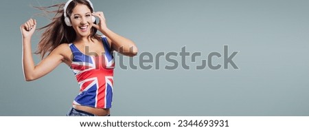 Smiling dancing girl wearing a British flag tank top and dancing, she is looking at camera