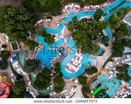 Aerial view of a vibrant scene of an aqua park from above, where people enjoy slides and pools. Laughter and joy fill the air. Royalty-Free Stock Photo #2344697473