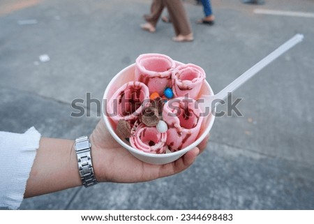 ice cream roll with strawberry flavor in white cartoon bowl, street food concept at culinary festival