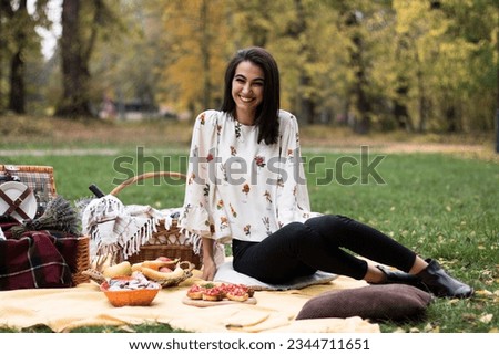 Young beautiful happy woman on a picnic in the park, waiting for her friends to arrive.
