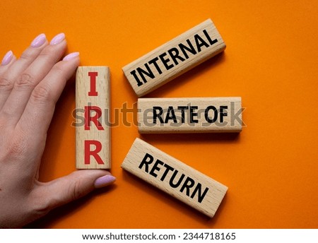 IRR - Internal Rate of Return symbol. Concept word IRR on wooden cubes. Businessman hand. Beautiful orange background. Business and IRR concept. Copy space. Concept word