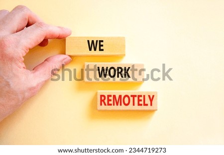 We work remotely symbol. Concept words We work remotely on wooden block. Beautiful white table white background. Businessman hand. Business we work remotely concept. Copy space.