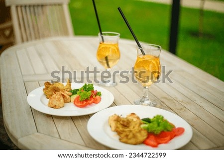 Beautifully served wooden table in natural boho style outdoors. Dining table decorated with cocktails, dishes and fresh food