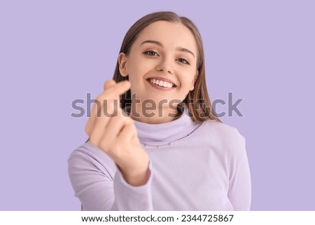 Young woman in sweater snapping fingers on lilac background, closeup Royalty-Free Stock Photo #2344725867