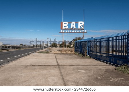 Sign of a bar and restaurant against a blue sky by the roadside in Spain