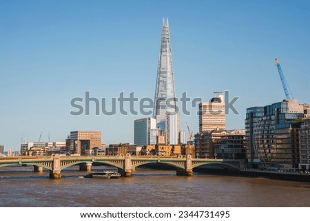 Shard tower amidst buildings with clear sky in background. Downtown district in city of London. Southwark bridge over river Thames on sunny day. Royalty-Free Stock Photo #2344731495