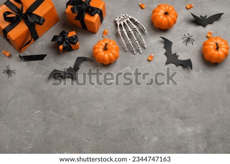 Composition with gift boxes, tasty candy corns, skeleton hand and Halloween decor on grey background