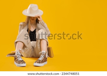Stylish woman posing in classic old school sneakers with leopard print on orange background, selective focus. Space for text