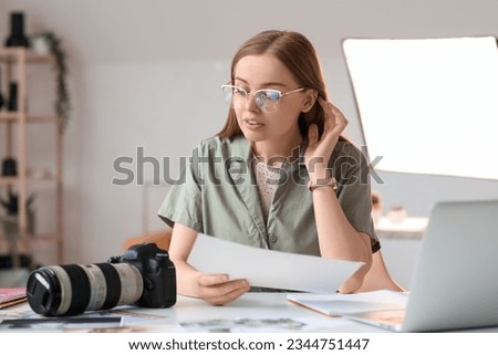 Young female photographer working at table in studio