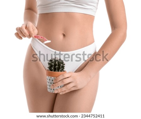 Young woman in underwear with razor and cactus on white background