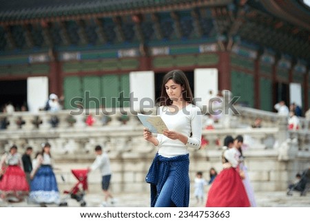 A young white female college student who finds her way while looking at a map in a traditional Korean village