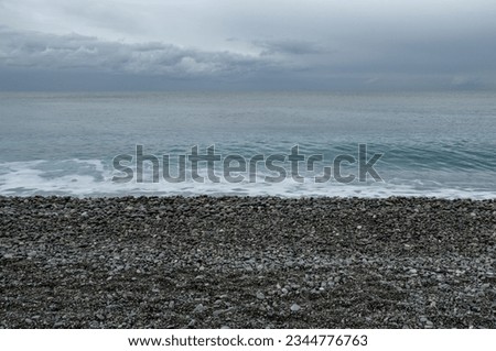 Stony beach with overcast sky in Nice, France Royalty-Free Stock Photo #2344776763