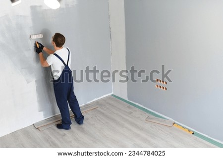 repair, building and home concept - close up of male in gloves holding painting roller. Royalty-Free Stock Photo #2344784025