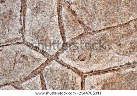 Stamped concrete mosaic patterns, earth tone colors and textures from directly above. A procedure of stamping cement to resemble tile, wood or other materials.
