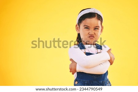Arms crossed, portrait and angry girl child in studio with bad, attitude or behavior problem on yellow background. Frown, face and asian kid with body language for no, frustrated or tantrum emoji Royalty-Free Stock Photo #2344790549