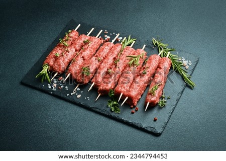 Lula kebab on skewers with spices in a black slate board on a stone background. Top view. Royalty-Free Stock Photo #2344794453