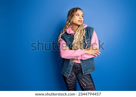 confident african american woman with dreadlocks posing and looking away on blue background Royalty-Free Stock Photo #2344794457