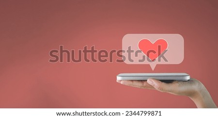 Social media,notification,,love mail,valentine day,Dating App concept.,Hand holding smartphone with love emoticon in speech bubble over pink background with copyspace perfect for technology idea. Royalty-Free Stock Photo #2344799871