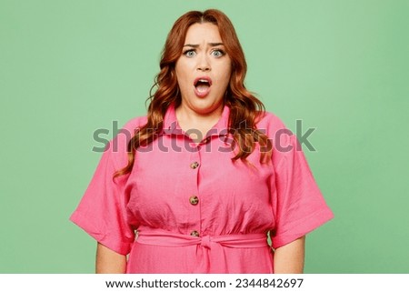 Young shocked astonished sad chubby overweight redhead woman wearing casual clothes pink dress looking camera with opened mouth isolated on plain pastel light green color background. Lifesyle concept Royalty-Free Stock Photo #2344842697