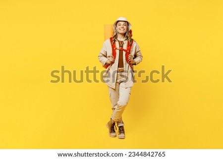 Full body smiling happy young woman carry bag with stuff mat look camera isolated on plain yellow background. Tourist leads active lifestyle walk on spare time. Hiking trek rest travel trip concept Royalty-Free Stock Photo #2344842765