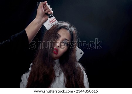 Beautiful black long hair woman with knife in head wearing white ghost spooky costume, scary dead corpse female was killed with knife in man hand in dark background, going to celebrate Halloween party