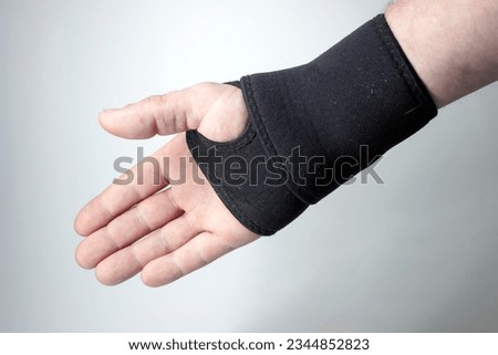 Injured hand with black elastic bandage on a gray background.