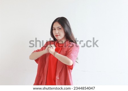 portrait of beautiful asian woman wearing red outfit with fist gesturing with serious expression isolated white background.