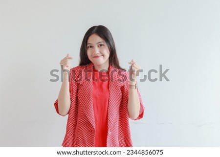 portrait of beautiful asian woman wearing red outfit with finger love gesture isolated on white background.