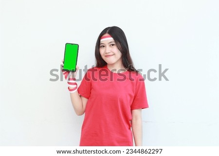 portrait of beautiful asian woman wearing red outfit celebrating Indonesia independence day by gesturing holding mobile phone isolated on white background.