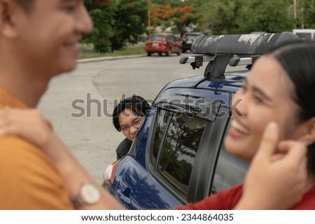 A creepy guy obsessively stalks a couple while hiding behind a car. An asian man obsessed over a woman who is in a relationship. Royalty-Free Stock Photo #2344864035