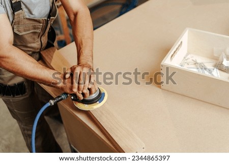 Close up of carpenter hands sanding wood with orbital sander at workshop Royalty-Free Stock Photo #2344865397