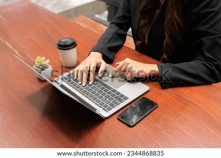 business woman sitting at desk with professional expression sitting at work with a tablet in hand occasional sip of coffee and manage mobile phones attentively. efficiently juggling her tasks staying.
