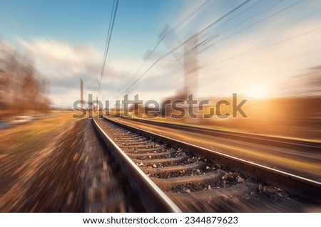 Railroad in motion at sunset. Railway station with motion blur effect against beautiful blue sky, Industrial concept background. Railroad travel, railway tourism. Blurred railway. Transportation Royalty-Free Stock Photo #2344879623