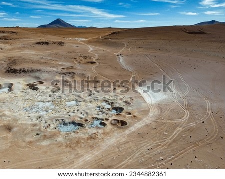 Bizarre beauty of the geothermic field Sol de Mañana with its steaming geysers and hot pools with bubbling mud viewed from above - traveling Bolivia