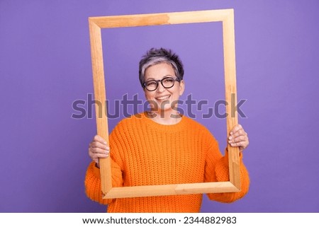 Portrait of good mood nice person with gray hairstyle wear knit jumper hold picture frame posing isolated on violet color background