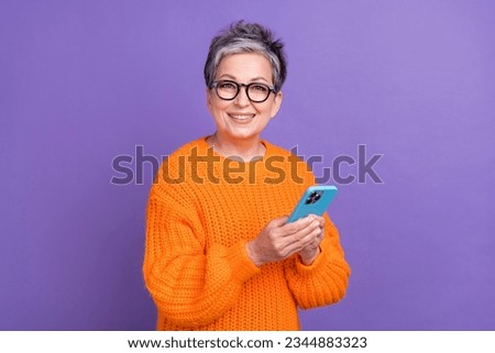Photo of charming pretty woman dressed orange sweater texting modern device isolated violet color background