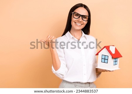 Photo of attractive real estate agency worker hold small house indicate finger empty space isolated on beige color background