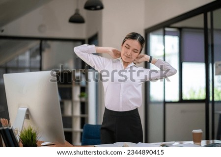 Businesswoman stretching lazy at the desk to relax while working in the office.