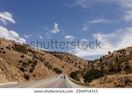 A beautiful highway among mountains with cars and trucks on sunny days. A landscape with transport. Bakersfield, California, USA - 7-22-2021