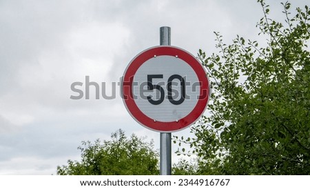 Circle road sign with number 50, installed beside a road in rural. Speed limit for 50 km. Warning to slow driving on street. Traffic sign. train track sign