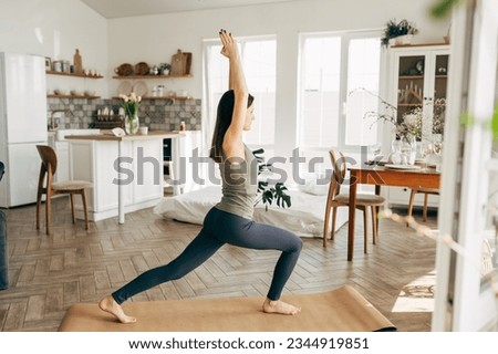Beautiful young woman practicing yoga at home Royalty-Free Stock Photo #2344919851