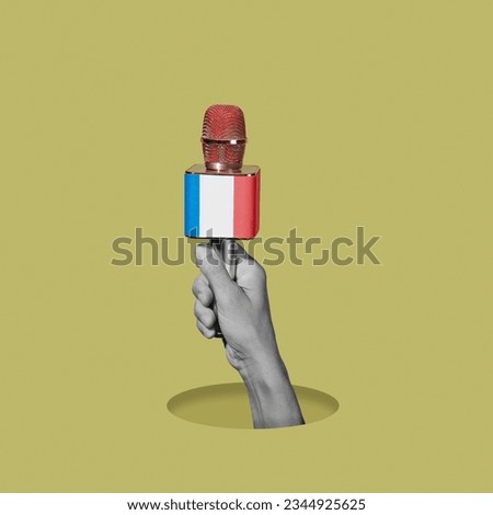 the hand of a man, in black and white, holding a microphone patterned with the flag of france, on a greenish yellow background